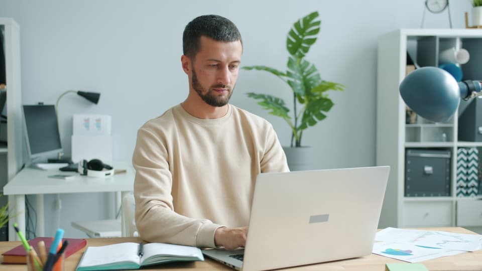Young professional working on laptop at desk — sell consumer loan portfolios on Debexpert